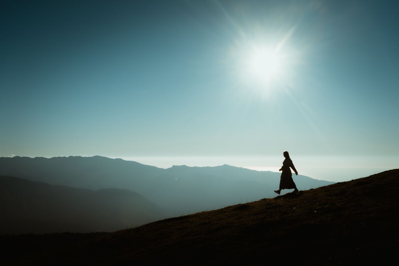 אדם הולך באור השמש על רקע הרים - חשיפה לשמש ליצירת ויטמין D